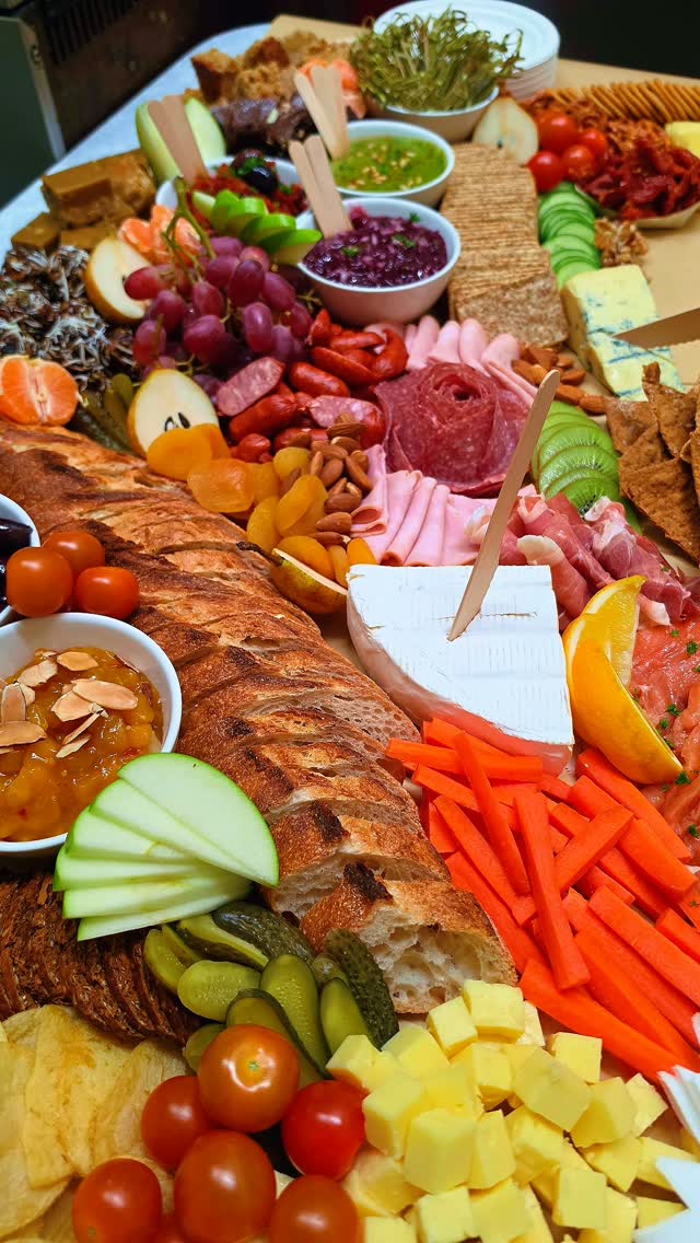 A grazing board with bread, meats, cheese, fruit and vegetables