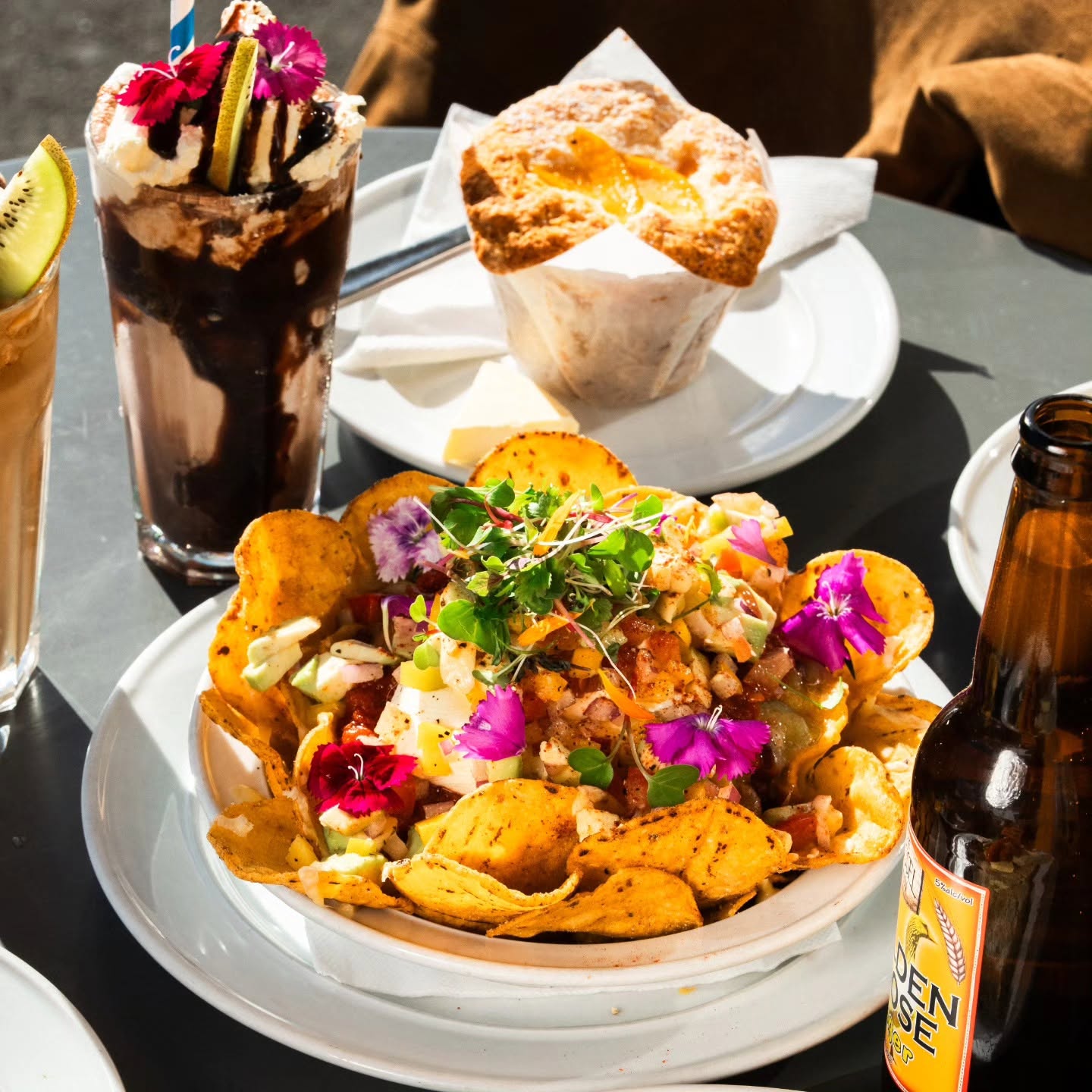 Loaded nachos topped with edible flowers, next to a craft beer